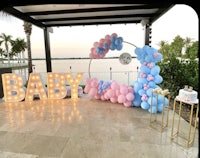 a baby shower with blue and pink balloons and a sign