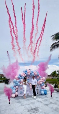 a couple standing in front of pink and blue smoke bombs