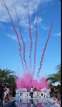 a girl boy party with pink and blue smoke erupting from a pool