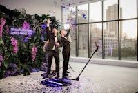 two people in tuxedos standing in front of confetti