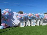 a baby shower balloon arch with blue and pink balloons