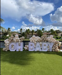 oh baby balloon sign in front of a grassy area